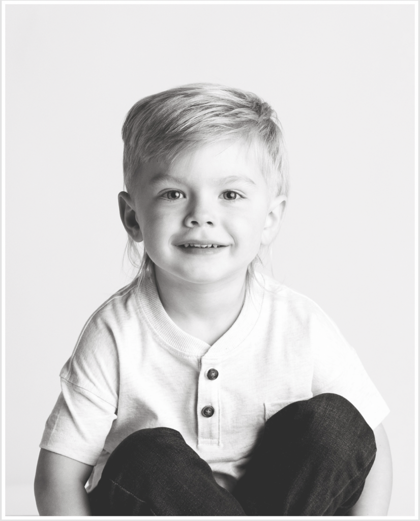 Boy sitting holding legs for his milestone session in black and white